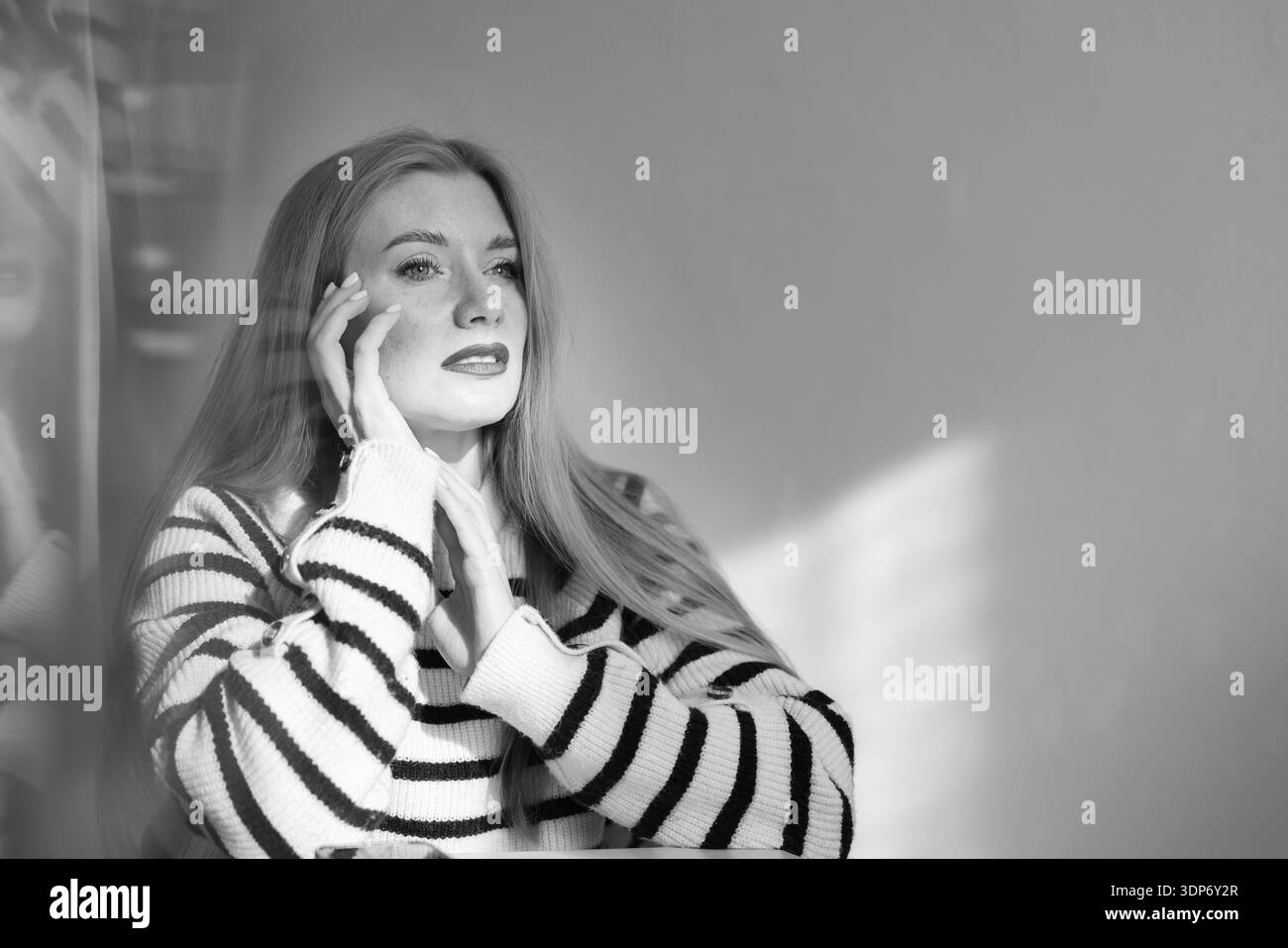 Ritratto in bianco e nero di una donna premurosa che guarda attraverso la luce della finestra. Concetto di stile di vita emotivo con spazio di copia. Foto Stock