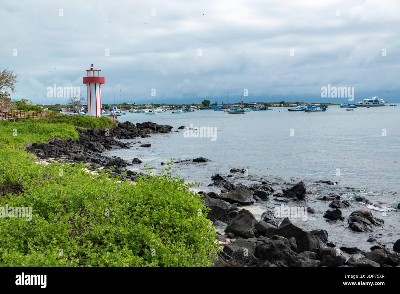 Faro di Playa Mann (San Cristobal, Galapagos): Vista panoramica di un'area costiera, caratterizzata da un faro con strisce rosse e bianche. Foto Stock
