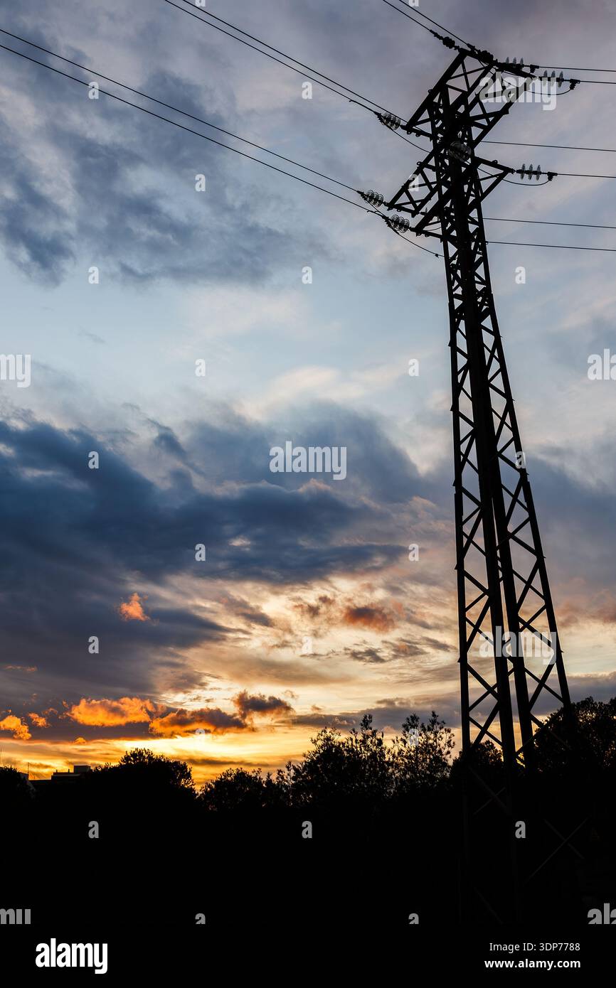 Una spettacolare ripresa ad angolo basso di un potente pilone che si erge alto contro un cielo arancione e blu intenso del tramonto, con le silhouette della città che fiancheggiano il botto Foto Stock