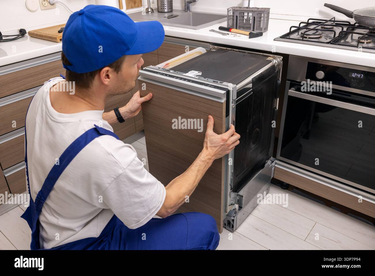 addetto all'assistenza che installa una lavastoviglie integrata in cucina. manutenzione e riparazione di elettrodomestici Foto Stock