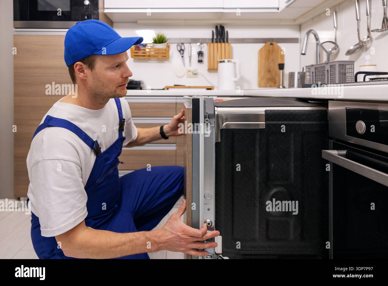 addetto all'assistenza che installa una lavastoviglie integrata in cucina. manutenzione e riparazione di elettrodomestici Foto Stock