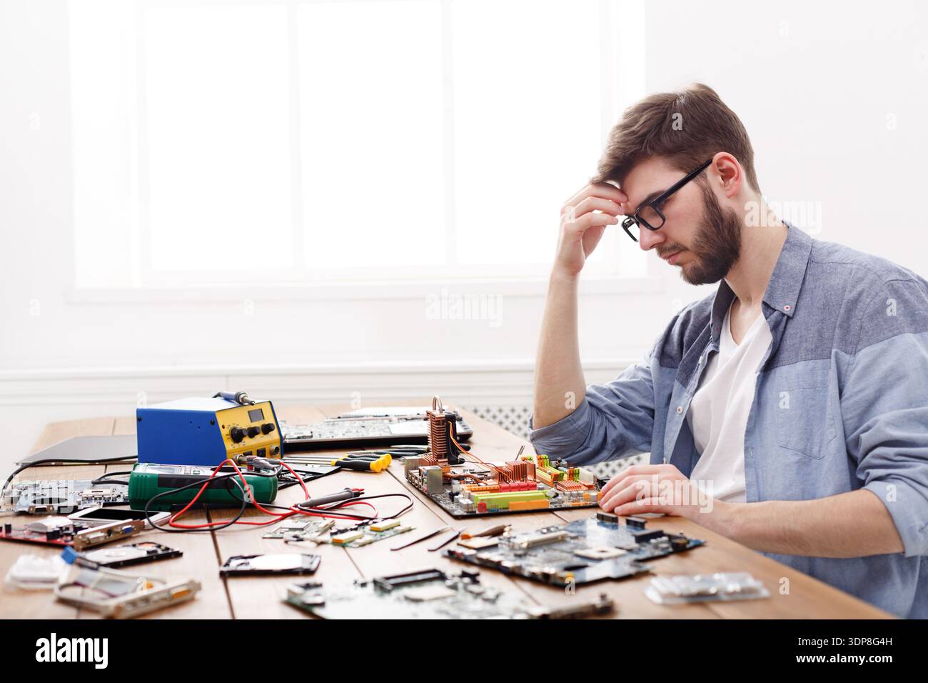 Persona che lavora su circuiti elettronici e componenti su un tavolo di legno Foto Stock
