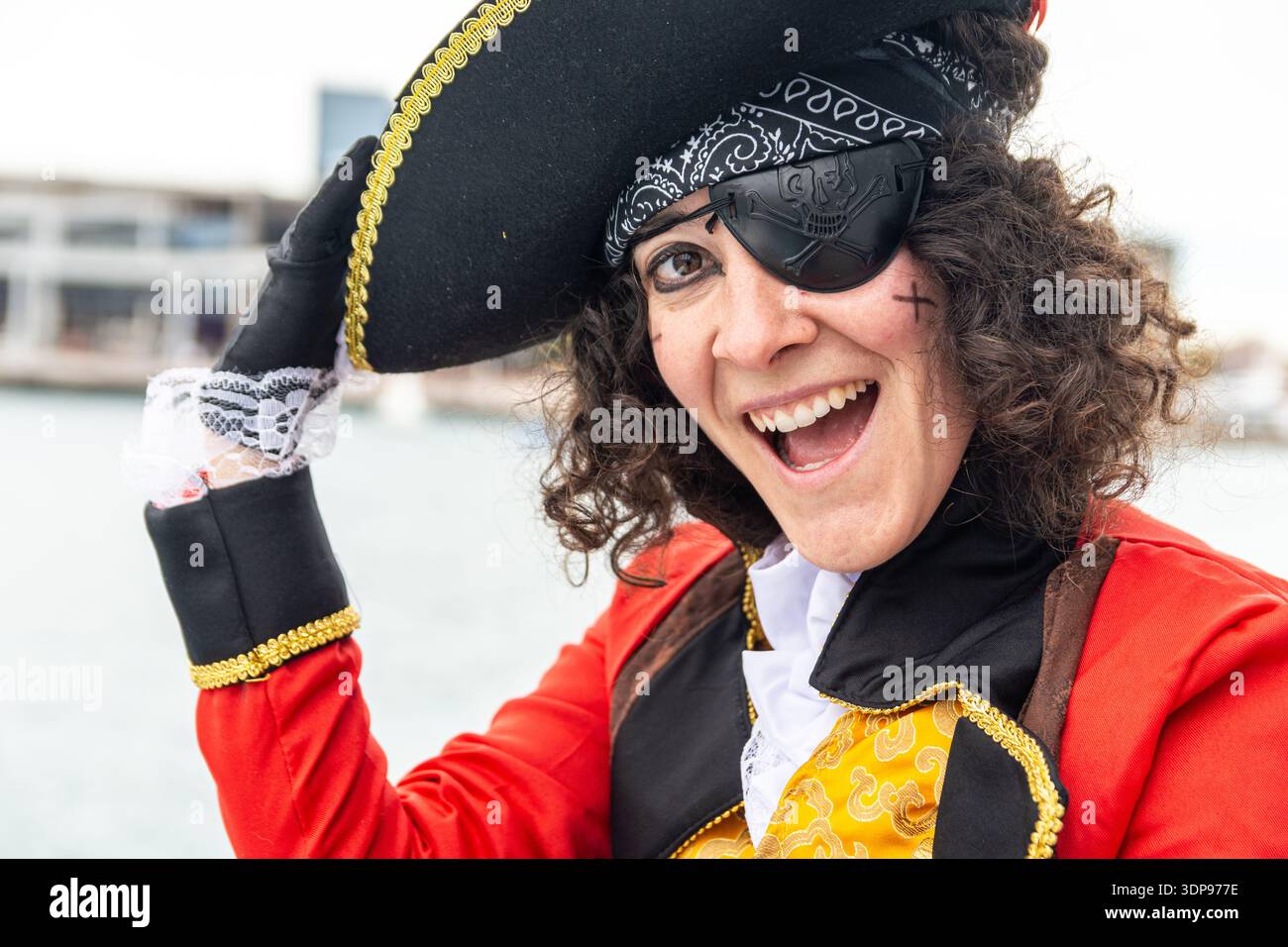 Donna vestita da pirata con un occhiello e un cappello tricorno, sorridendo e ridendo durante una divertente festa di carnevale, godendosi l'atmosfera festosa Foto Stock