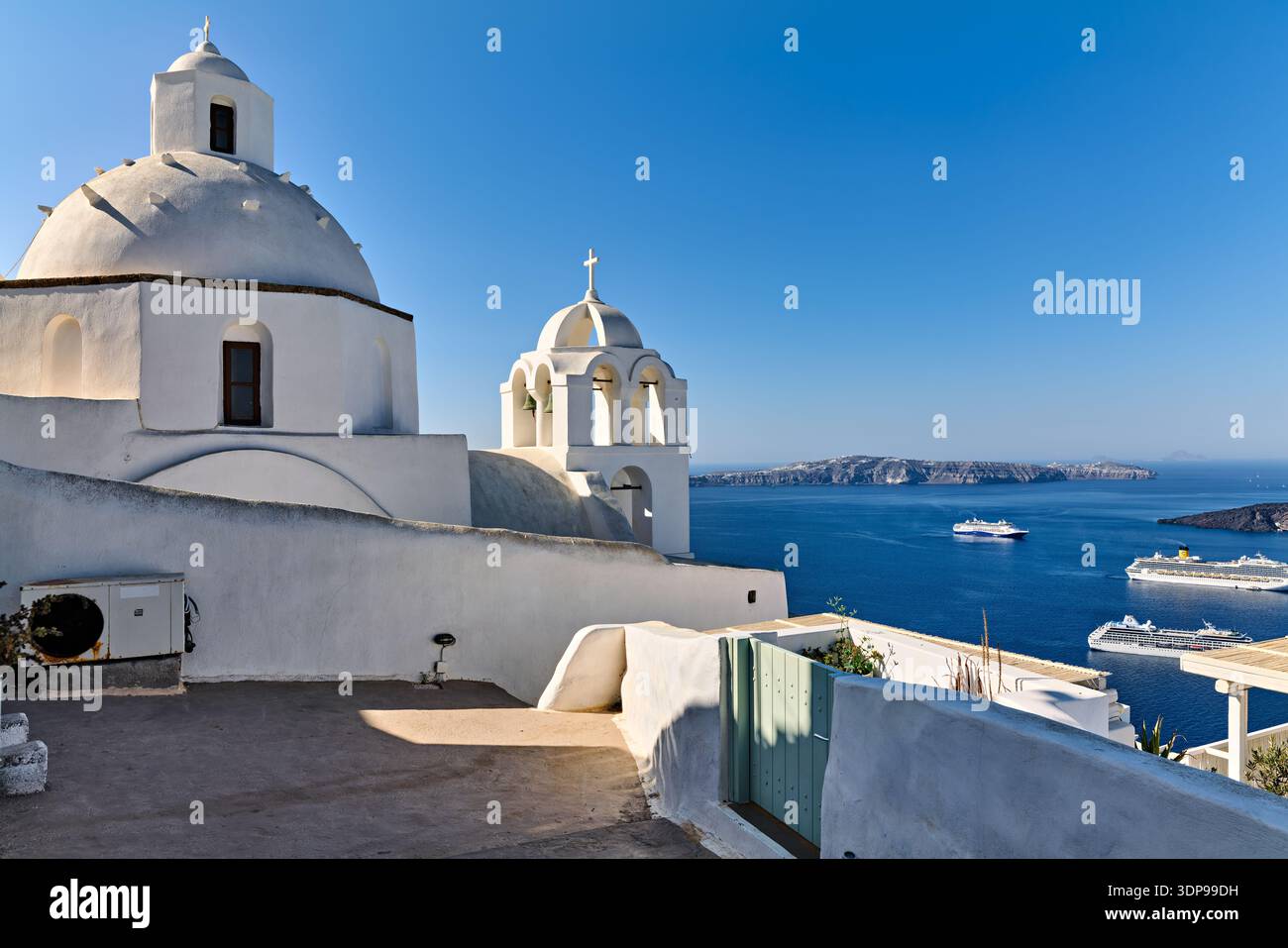 Le chiese bianche si affacciano sulla caldera di Santorini, in Grecia, mentre le navi da crociera portano i turisti a godersi le iconiche vedute dell'isola. Foto Stock