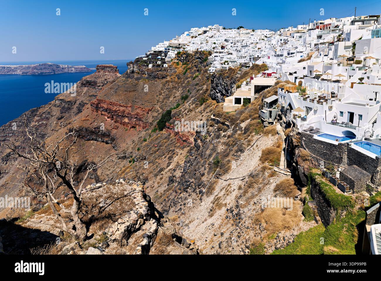 Santorini, Grecia: Edifici imbiancati cadono a cascata lungo le scogliere vulcaniche, offrendo splendide vedute del Mar Egeo e della caldera, una popolare destinazione turistica Foto Stock