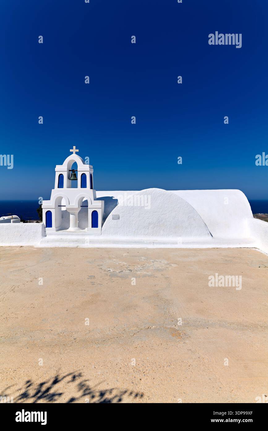 Una classica chiesa greco-ortodossa bianca e blu sotto un cielo azzurro, tipica delle isole Cicladi, che offre una vista serena del Mar Egeo. Foto Stock