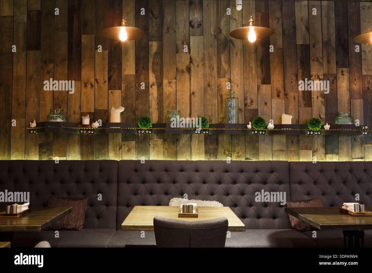 Accogliente interno in legno di un moderno ristorante con comodi posti a sedere e illuminazione ambientale Foto Stock