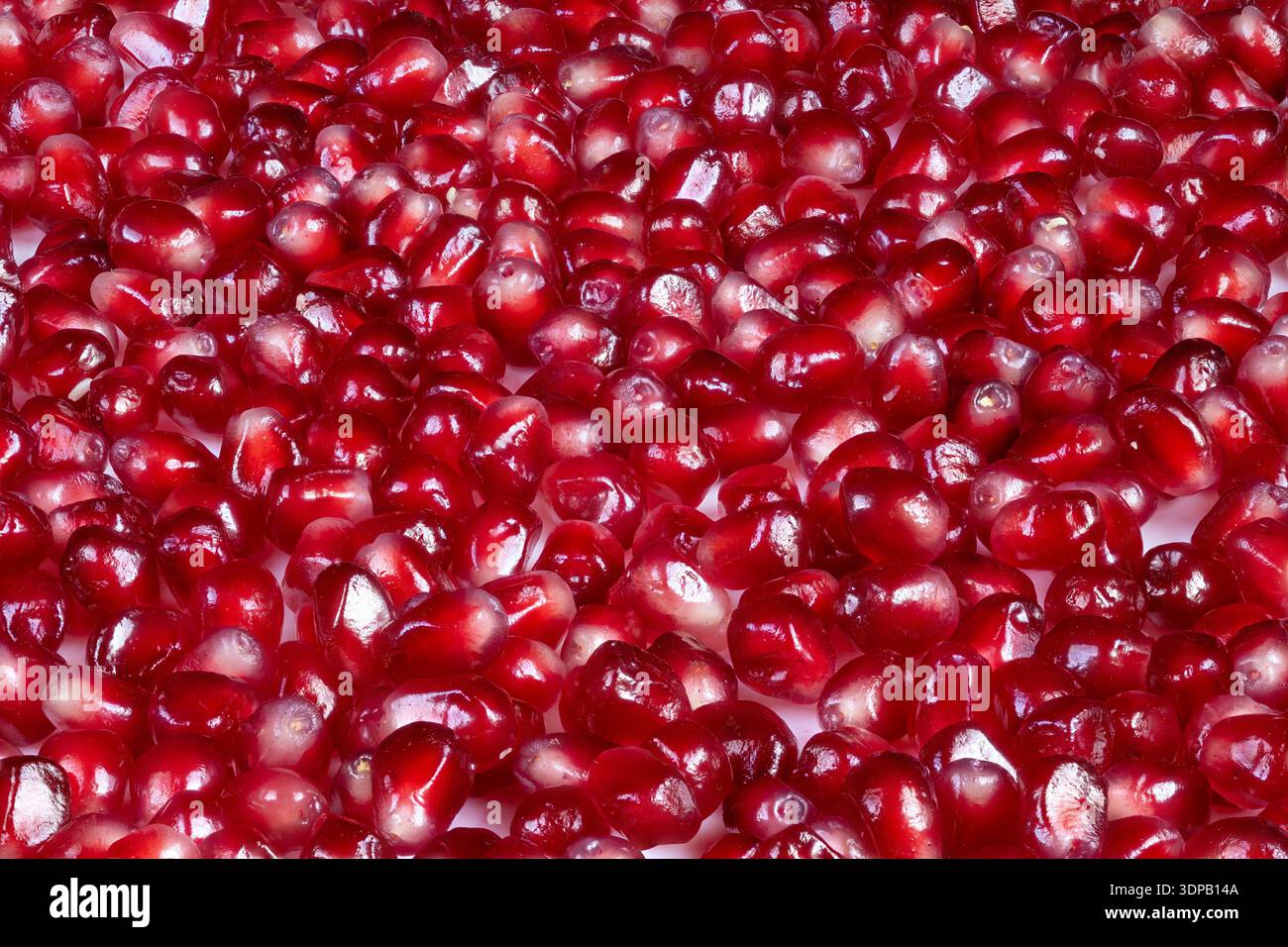 Motivo di semi di melograno brillante, texture gioiello con riflessi, ripetizioni macro strette che creano sfondo decorativo, pubblicità e pacchetti Foto Stock