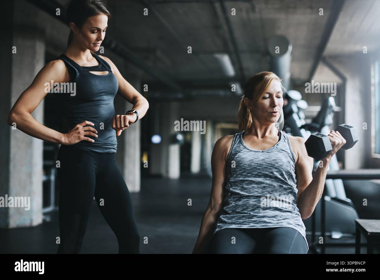 Fitness, coach o donne con manubri in palestra, performance temporali o allenamento di forza per l'allenamento. Sollevamento pesi, sfida o persona con istruttore Foto Stock