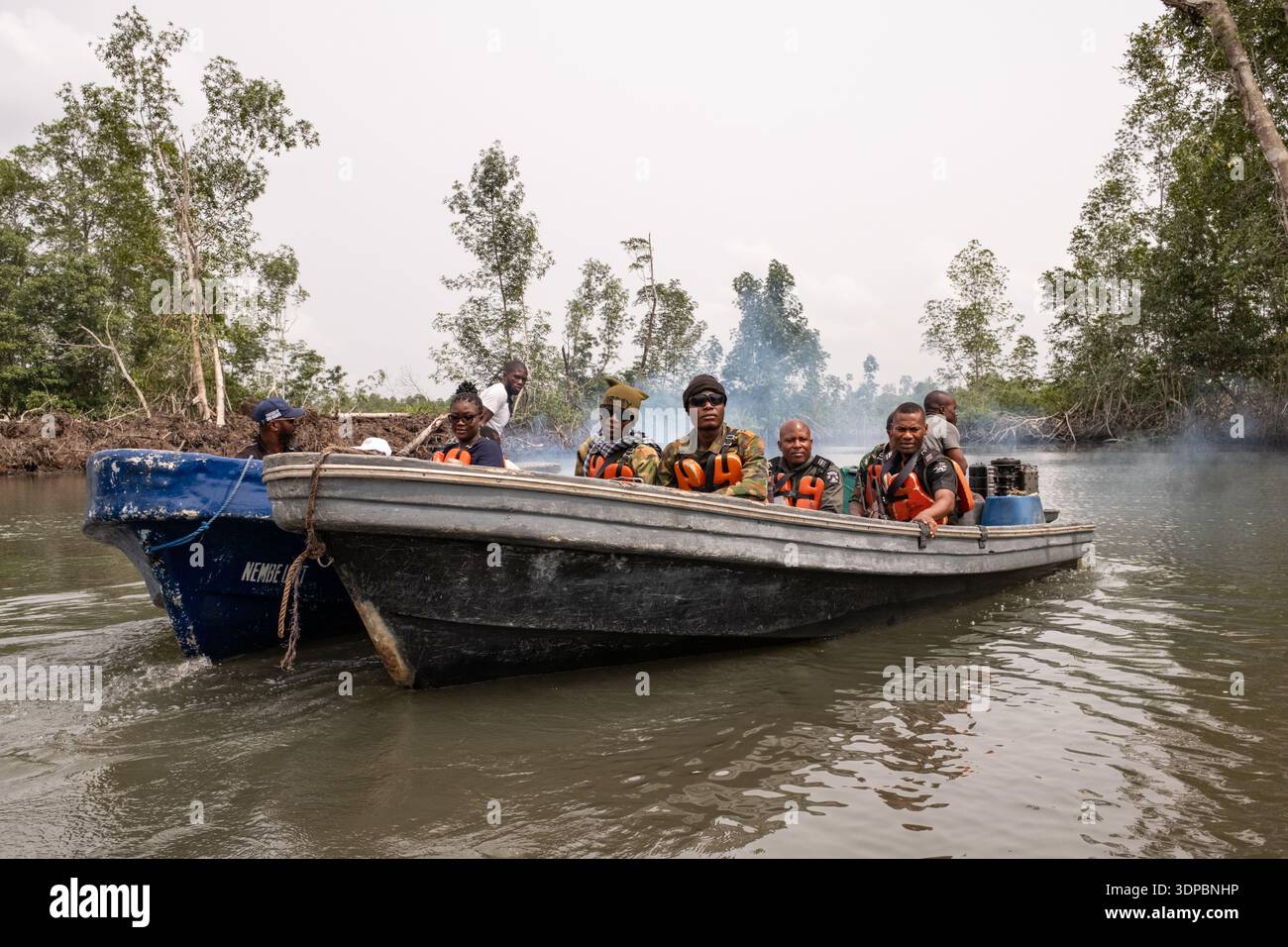 Personale di sicurezza che viaggia in motoscafo attraverso i corsi d'acqua di mangrovie nel Delta del Niger, nello stato di Bayelsa, Nigeria. Foto Stock