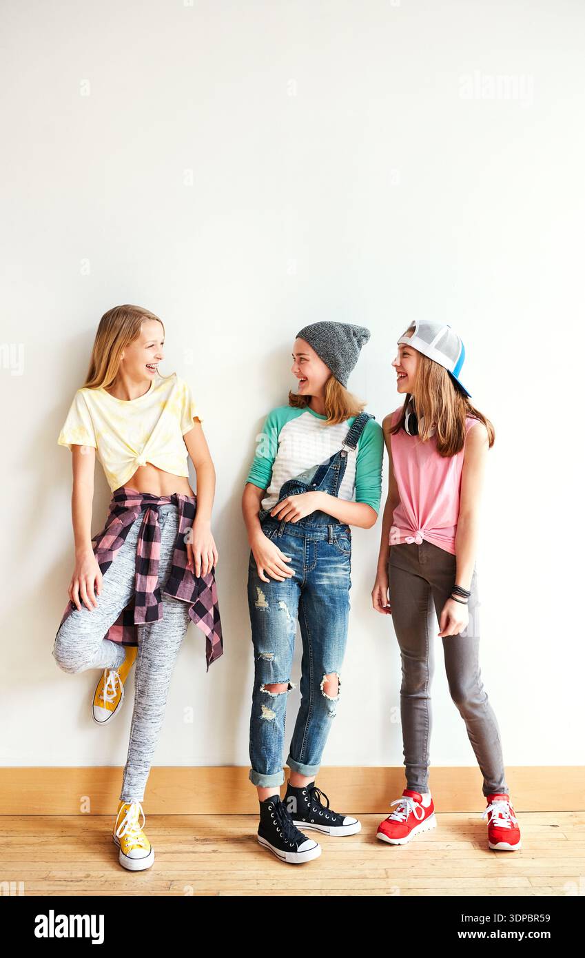 Moda, conversazione e gruppo di adolescenti al muro per legarsi, amicizia o ridere insieme. Felice, spazio e ragazze che escono con il figo Foto Stock