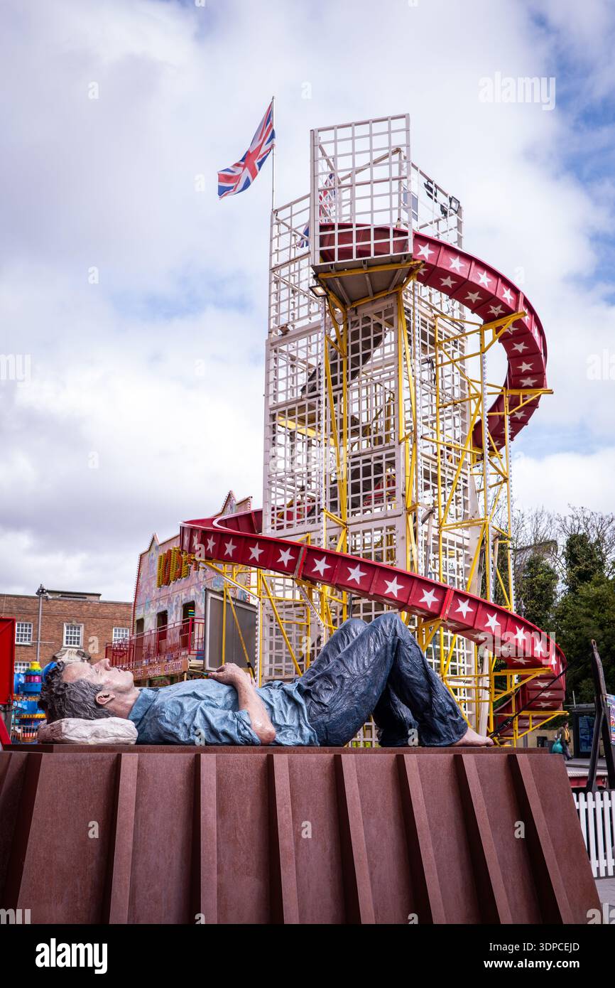 La gigantesca scultura reclinabile di Sean Henry con giro in fiera e bandiera Union Jack nel centro di Woking, in Inghilterra Foto Stock