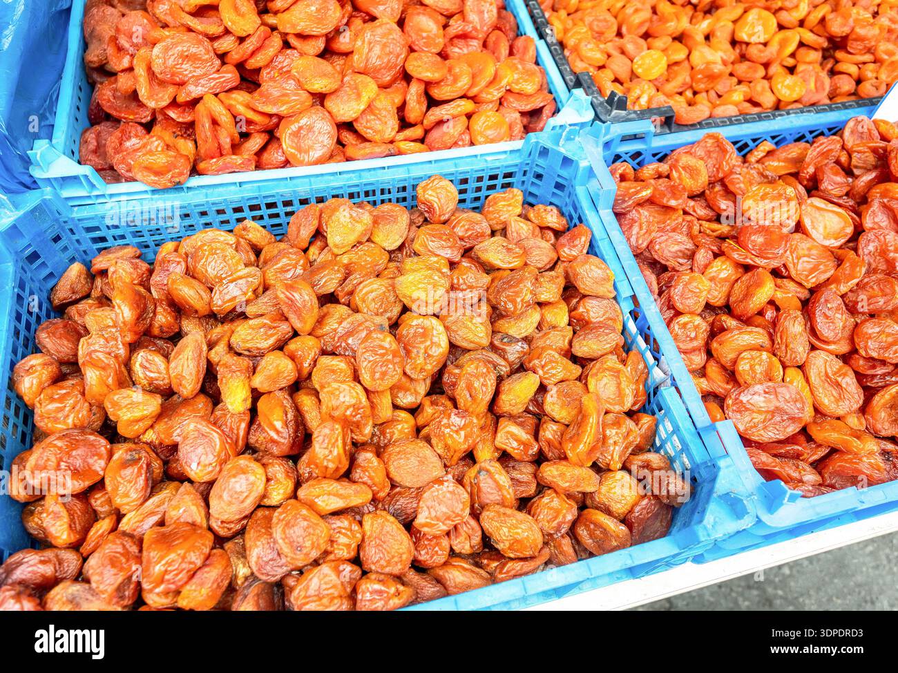 Albicocche secche uzbeke biologiche in casse di plastica in un mercato agricolo locale. Grande pila di albicocche secche, frutta secca, dessert sano, cibo vegetariano Foto Stock
