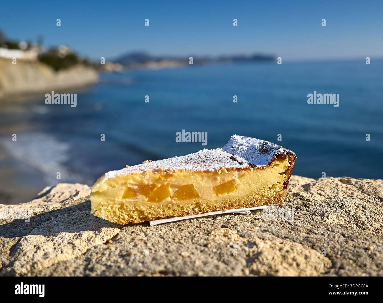 Fetta di torta di frutta artigianale con pezzi di pesca e zucchero a velo sulla costa mediterranea, Calpe, Costa Blanca, Spagna Foto Stock