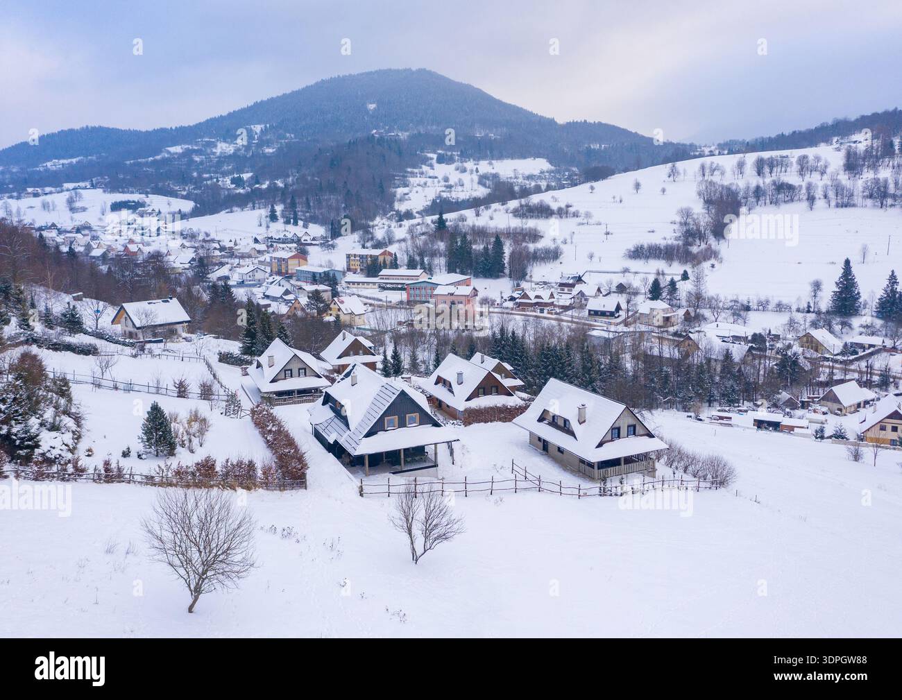 Vista aerea delle tradizionali cabine in legno nel villaggio innevato di Terchova, sulle montagne di Mala Fatra in Slovacchia, con paesaggio invernale con insenatura di neve bianca Foto Stock