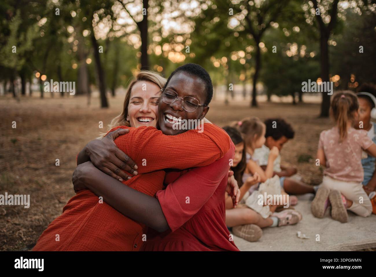 Due allegre insegnanti donne che si abbracciano in un parco Foto Stock