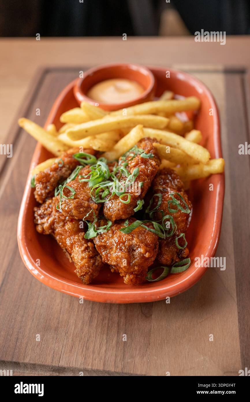Ali di pollo deliziosamente speziate servite con patatine fritte e salsa Foto Stock