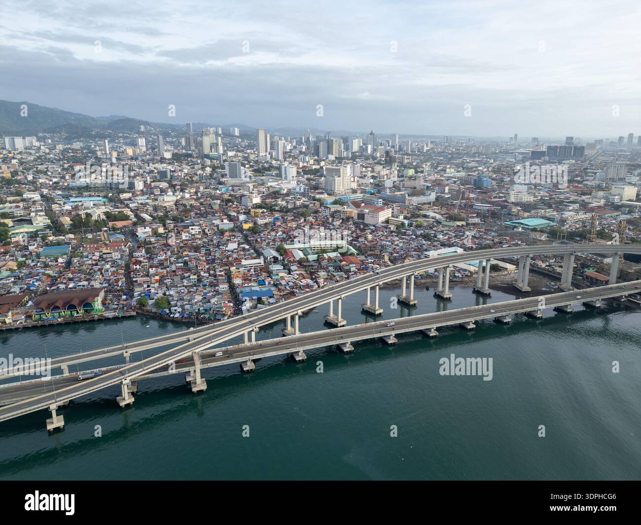 Vista aerea dello skyline di Cebu e dell'autostrada costiera con dense abitazioni urbane e infrastrutture di ponti che mostrano la crescita e lo sviluppo nelle Filippine. Foto Stock