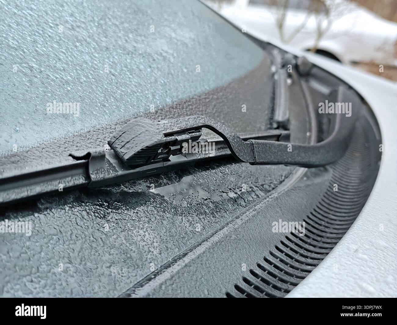 Primo piano del tergicristallo dell'auto ghiacciato ricoperto di ghiaccio e ghiaccio sul vetro durante il freddo inverno, trama dettagliata di gocce d'acqua ghiacciata su vehic Foto Stock
