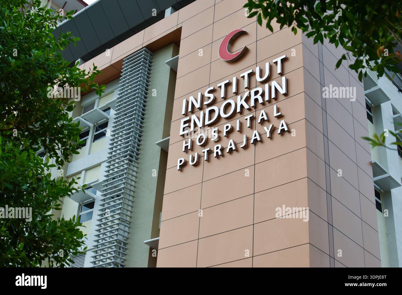 Esterno dell'Institut Endokrin Hospital Putrajaya con pannelli beige e arancioni, ombrelloni, insegne e design architettonico moderno Foto Stock