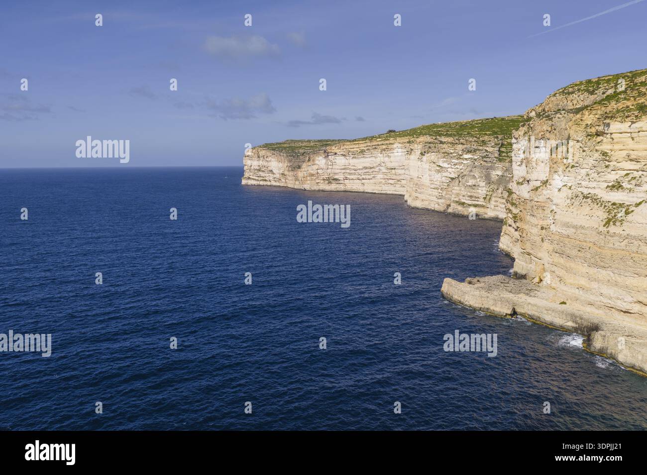 Vista aerea delle aspre scogliere a strati che incontrano il mare blu profondo, creando un incredibile contrasto di texture e tonalità, Xlendi, Baia di Xlendi, Malta. Foto Stock