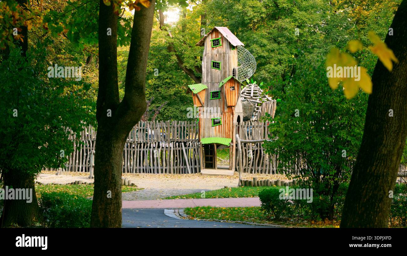 Un fantastico teatro di legno a più livelli sorge alto tra alberi e fogliame vibranti, circondato da una recinzione e da sentieri rustici Foto Stock