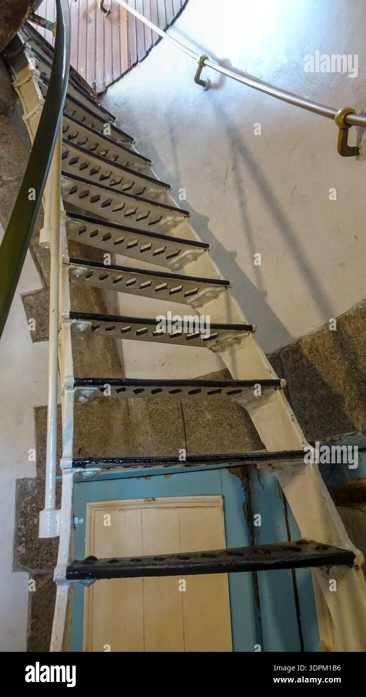 Un'elegante scala a chiocciola in ferro con ringhiera in metallo si snoda verso l'alto in uno spazio interno, mostrando dettagli architettonici e maestria artigianale. Foto Stock