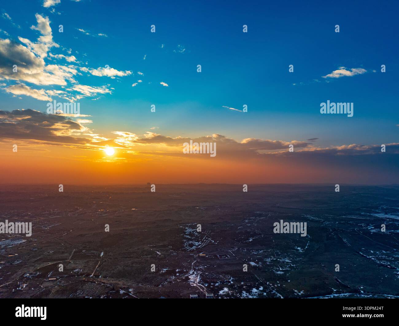 Il cielo è una bella tonalità di blu con un sole arancione brillante sullo sfondo. Il sole sta tramontando, creando un'atmosfera calda e tranquilla Foto Stock