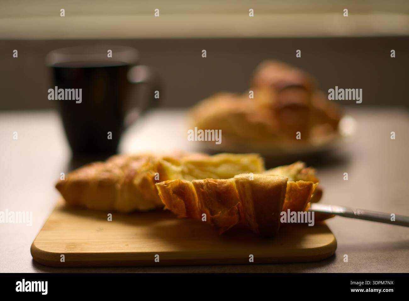 Croissant su un tagliere con una tazza di tè caldo. Foto Stock