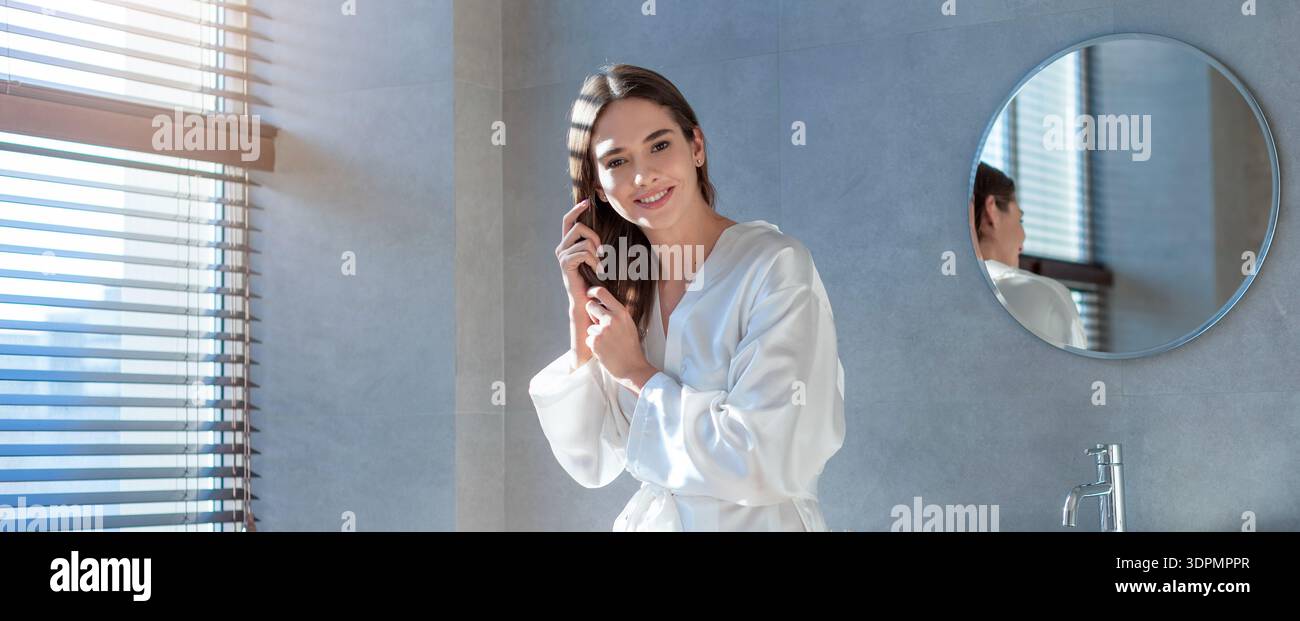 Donna che si prepara in un bagno con la luce del giorno che arriva dalla finestra al mattino Foto Stock
