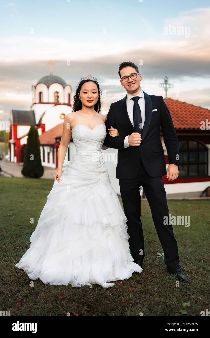 Coppia interrazziale che celebra il giorno del matrimonio fuori dalla chiesa Foto Stock