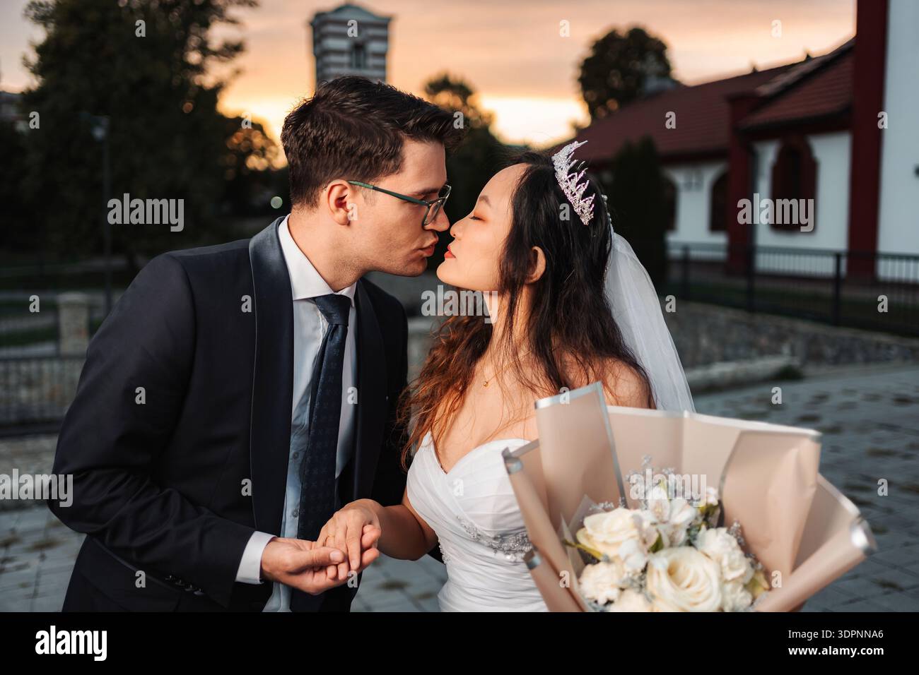 Matrimonio birazziale con coppia baciato durante la romantica cerimonia del tramonto Foto Stock