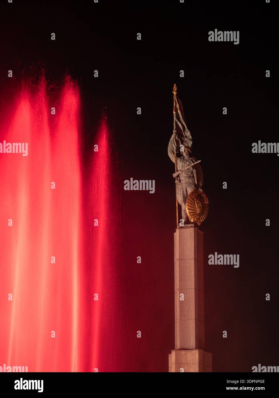 Memoriale di guerra sovietico Schwarzenbergplatz Vienna: Statua del soldato con bandiera e fucile, fontane rosse a getti di notte. Foto Stock