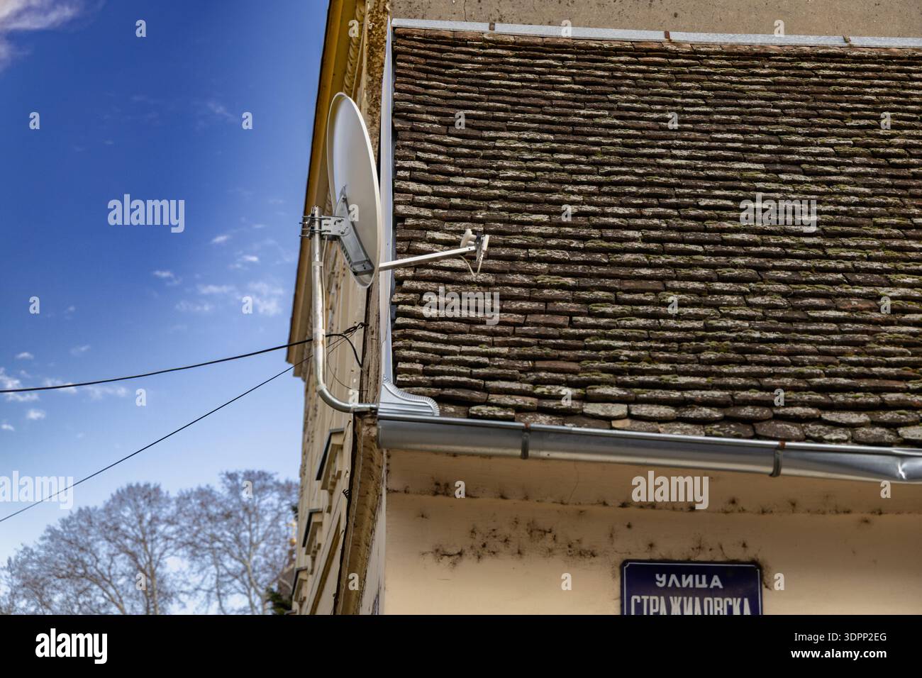 Vecchio edificio rustico con piatto satellitare sul tetto Foto Stock