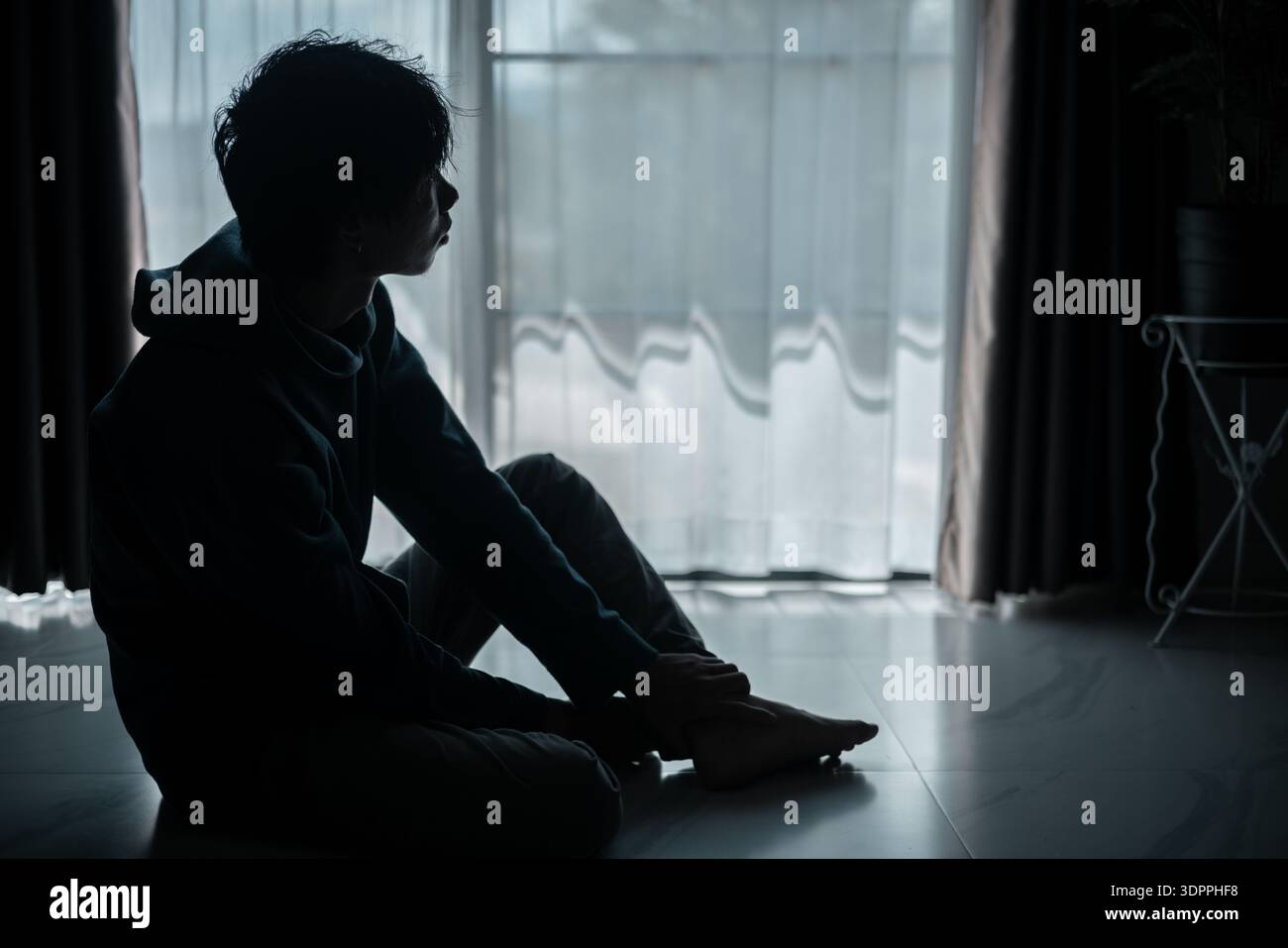 Silhouette di una lunga ombra perduta, che incarna profonda disperazione e disperazione, lo ha lasciato sempre stressato, triste e infelice. l'uomo sedeva da solo, f Foto Stock