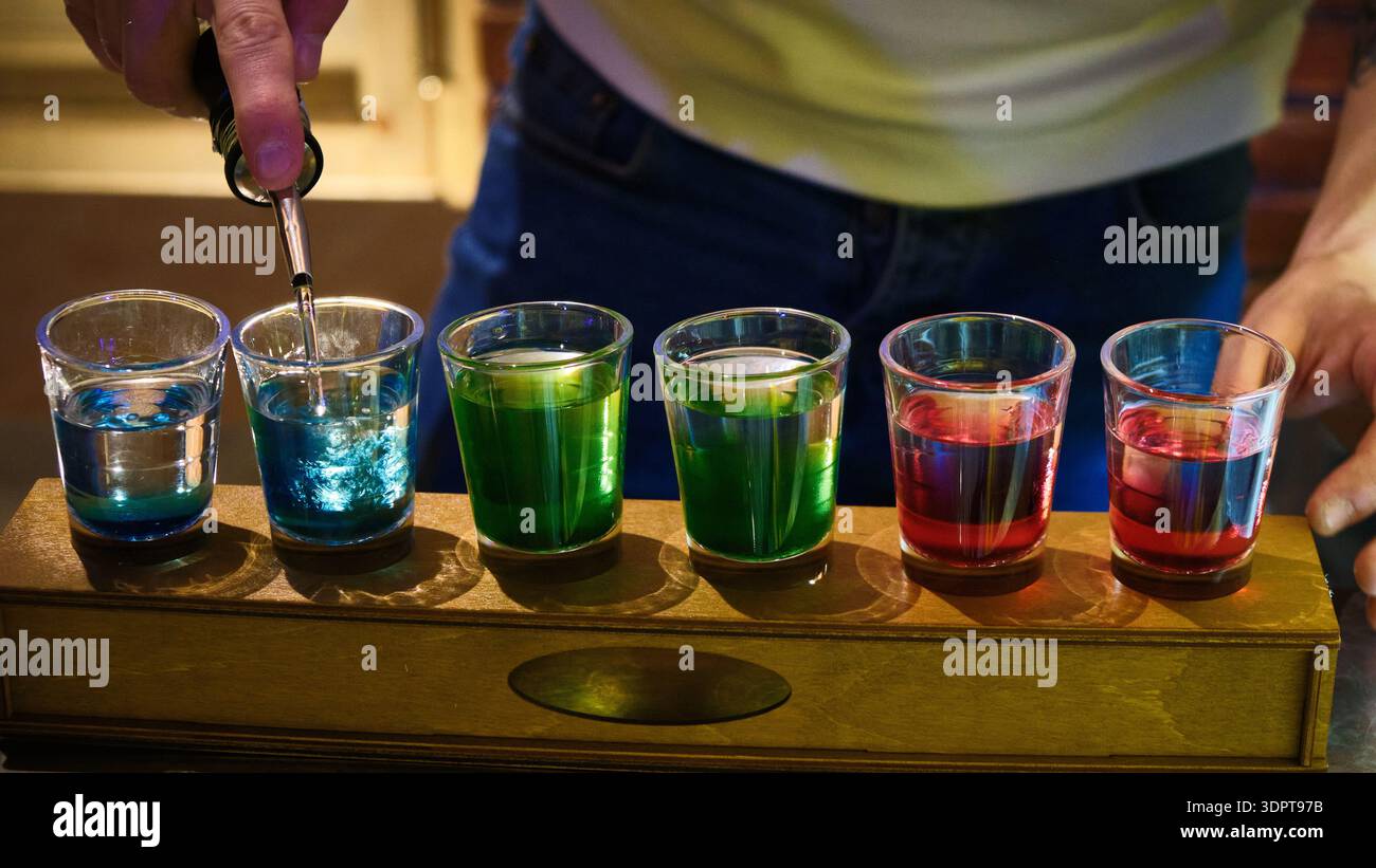 Bicchieri da shot colorati con cocktail a strati al bancone del bar Foto Stock