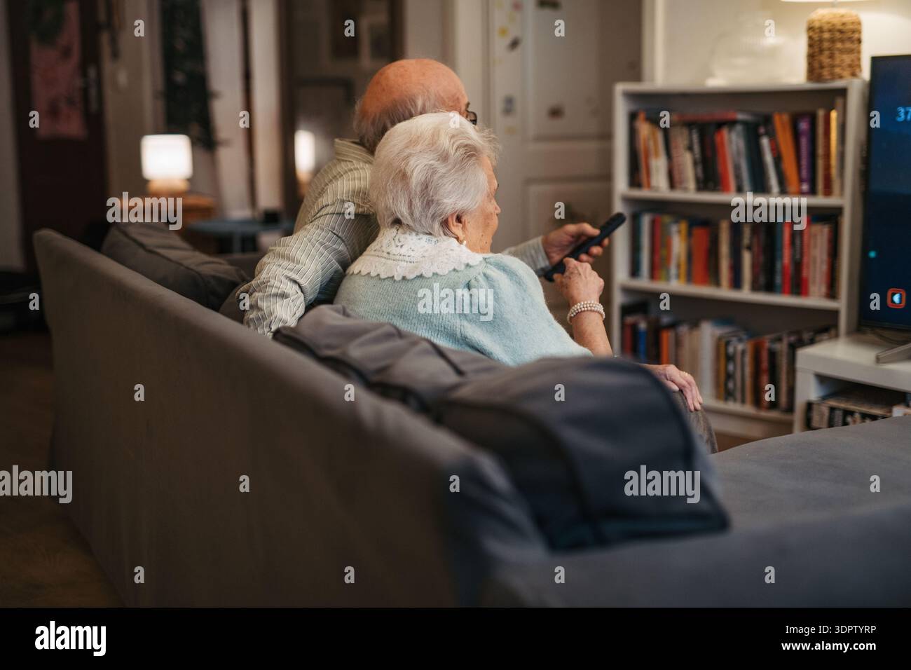 Bella coppia di anziani che guardava la televisione la sera. Foto Stock