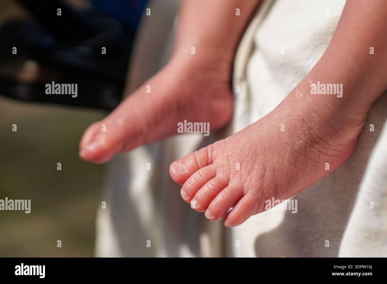 Foto dettagliata di primo piano orizzontale che cattura la delicata pelle rosa e le rughe dei piccoli piedi e delle dita dei piedi del neonato, appoggiati delicatamente Foto Stock
