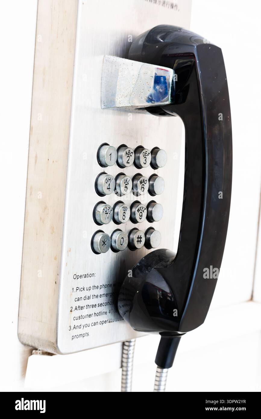 Telefono pubblico vintage con ricevitore nero montato a parete in ambiente urbano Foto Stock