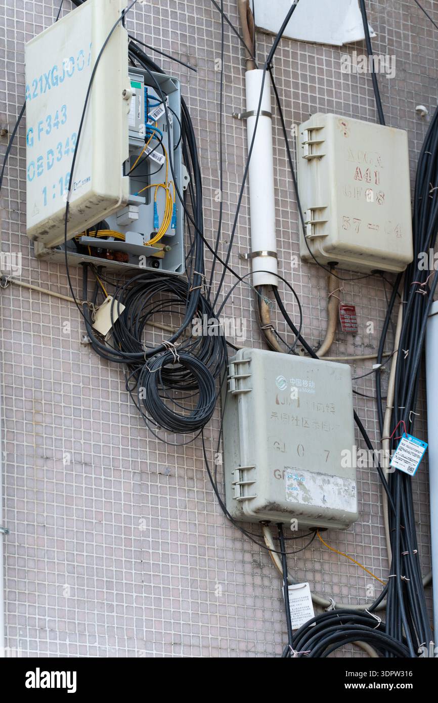 Scatole per uso esterno con cavi aggrovigliati montati su pareti piastrellate, infrastrutture urbane in Asia Foto Stock