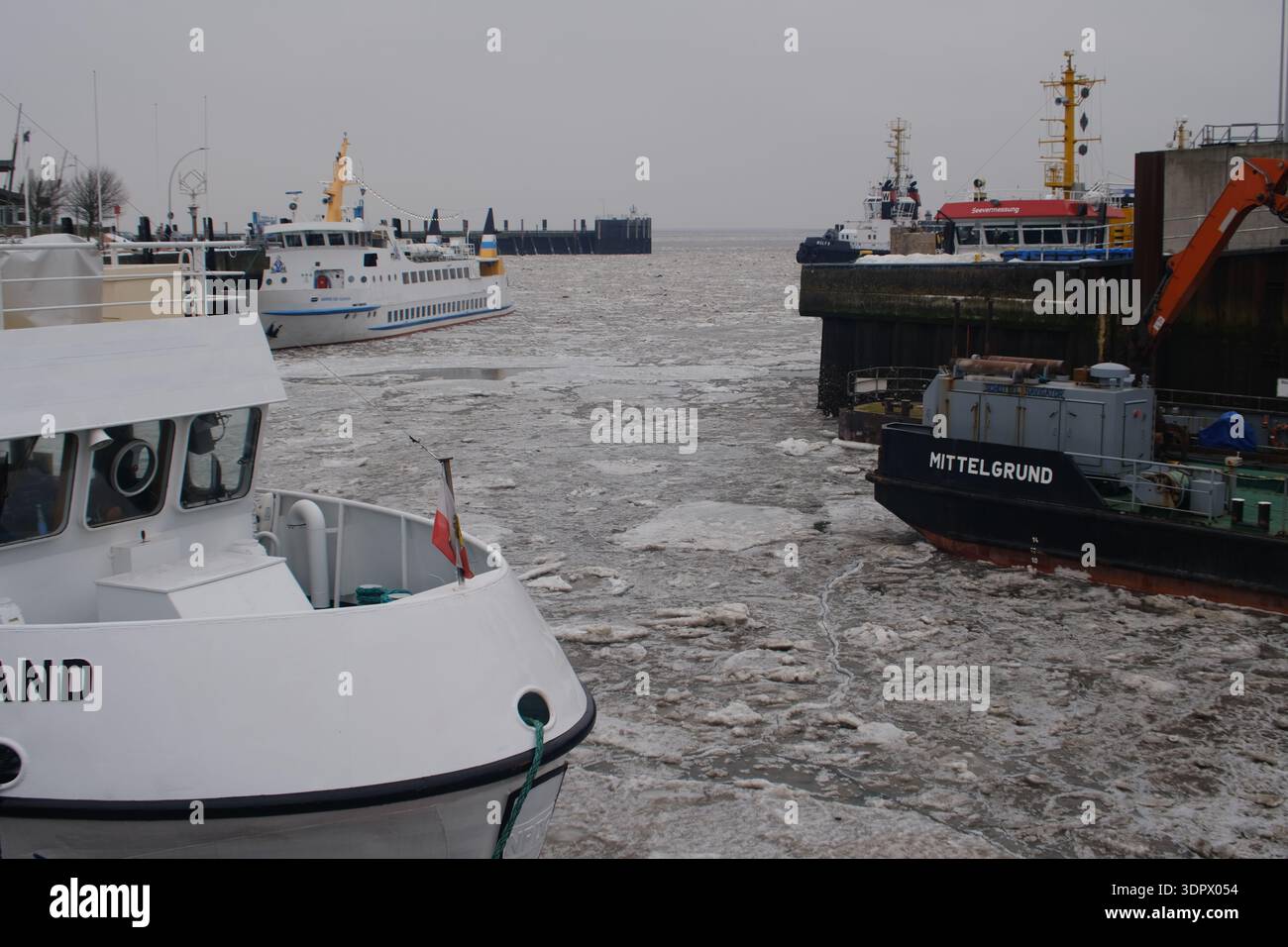 Navi da lavoro che navigano in un porto ghiacciato, illustrano le operazioni marittime invernali, la logistica portuale e il trasporto industriale. Foto Stock