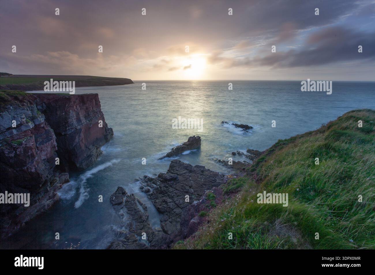 Spettacolare scogliera e macchia di mare al tramonto con un cielo scintillante sulla costa del Pembrokeshire, Galles. Foto Stock