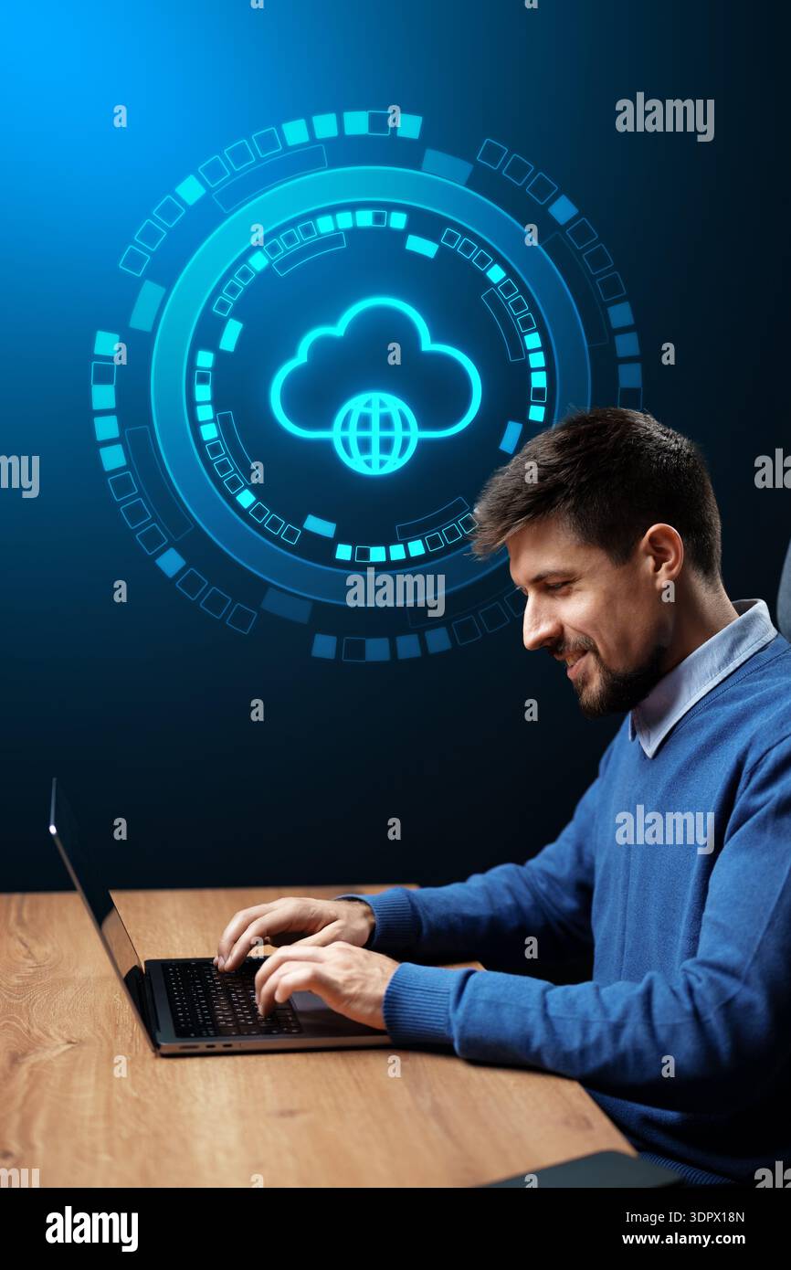 L'uomo lavora su un notebook con grafica basata su tecnologia cloud in background in un ambiente moderno Foto Stock