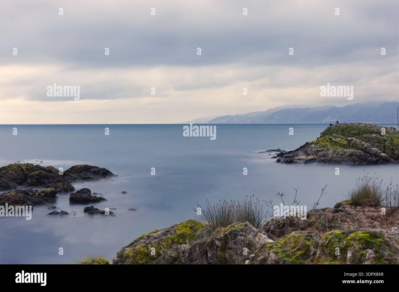 Calmo Seascape con Rocky Islet e Long Exposure Water foto minimalista del paesaggio marino con un piccolo isolotto roccioso circondato da acque lisce come seta Foto Stock