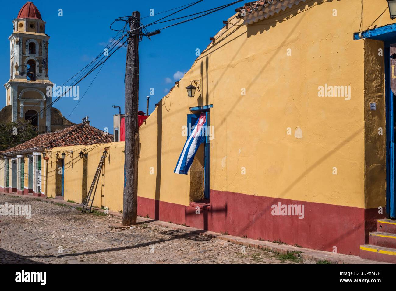 Bandiera cubana esposta su una porta di legno blu adagiata su una facciata coloniale gialla a Trinidad, Cuba Foto Stock