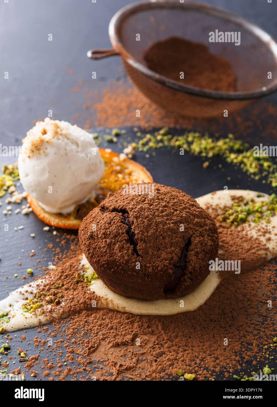 Dessert al cioccolato servito con gelato e guarnito con pistacchi e buccia d'arancia Foto Stock