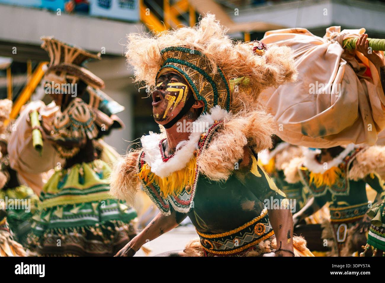 Iloilo City, Filippine - 25 gennaio 2026: Veduta di una vibrante ballerina del festival ATI-Atihan, faccia dipinta con colpi audaci, in mezzo a un vortice di piume Foto Stock