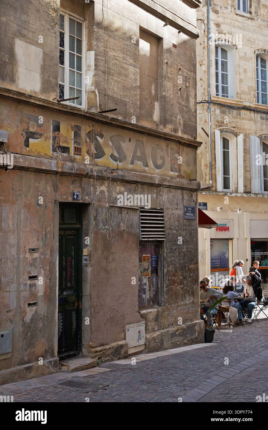 Cartellone sbiadito del negozio "Plissage" su un edificio storico in una stradina stretta con caffè nella città vecchia di Avignone, Provence-Alpes-Côte d'Azur, Francia Foto Stock