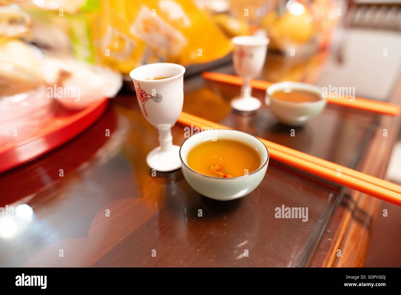 Preparazione della cerimonia del tè cinese con tazze in ceramica, bastoncini e tè caldo su un tavolo in legno lucido Foto Stock