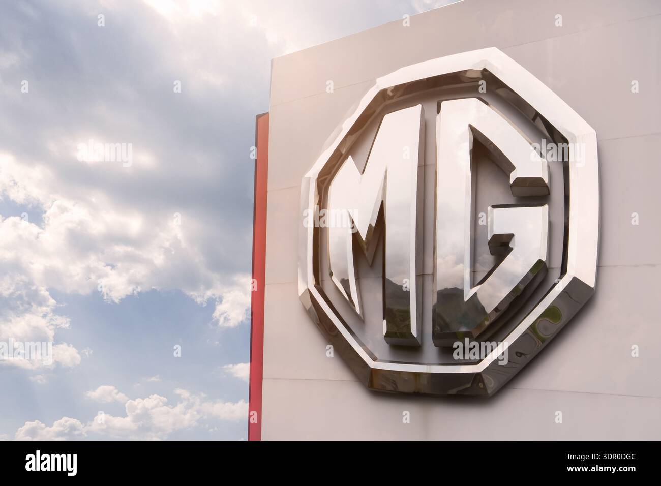 Phuket Thailandia 25 11 2025: MG - il logo del marchio MG Motor in lettere cromate lucide su uno scaffale vicino alla concessionaria è il vecchio marchio britannico di Morris Foto Stock
